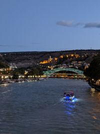 View of river amidst illuminated buildings in city