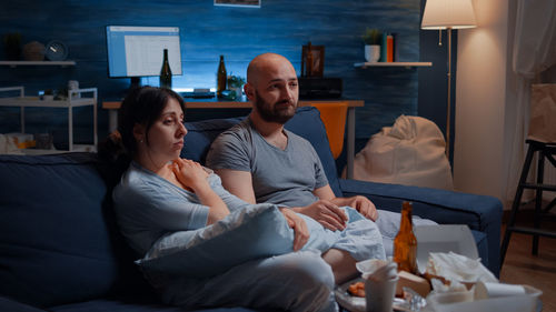 Couple watching movie while sitting on sofa at home