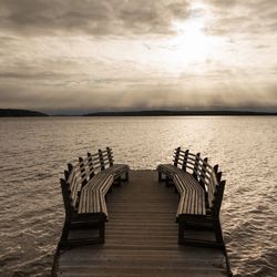 Wooden pier over sea against sky during sunset