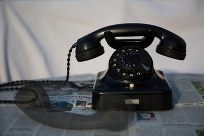 Double exposure of old-fashioned rotary phone on table