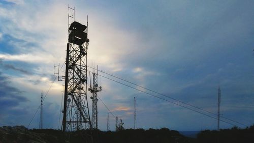 Low angle view of silhouette electricity pylon against sky during sunset