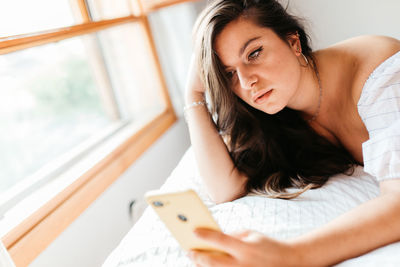 Portrait of young woman using laptop on bed at home