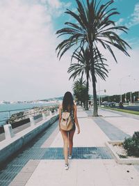 Silhouette of woman standing by palm tree