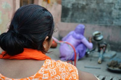 Rear view of woman sitting outdoors