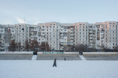 Buildings on snow covered field against sky