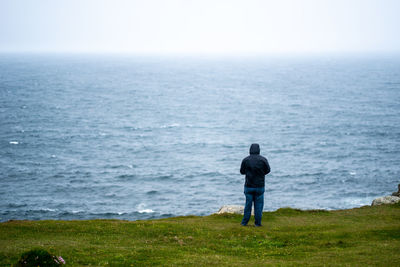 Rear view of man looking at sea against sky