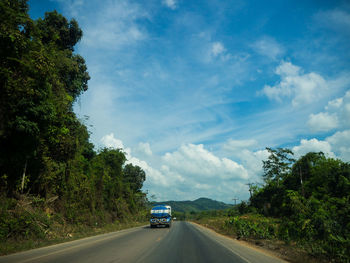 Road amidst trees against sky