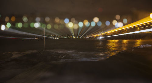 Illuminated bridge over river against sky at night