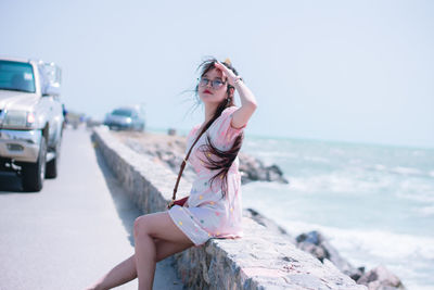 Young woman wearing sunglasses on sea against sky
