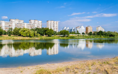 Scenic view of lake by buildings against blue sky