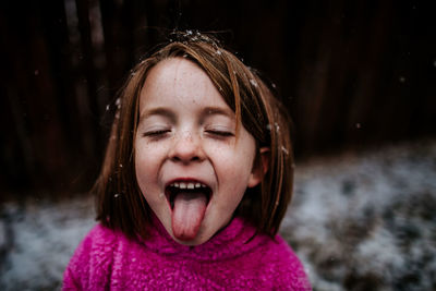 Young girl trying to catch snow flakes on her tongue in winter