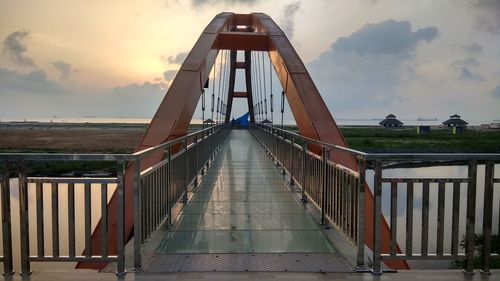 Footbridge against sky at sunset