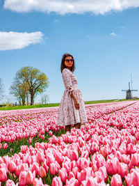 Woman standing by pink flowering plants on field