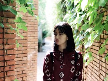 Young woman standing against brick wall