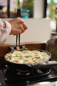 Cropped hand of person preparing food in kitchen