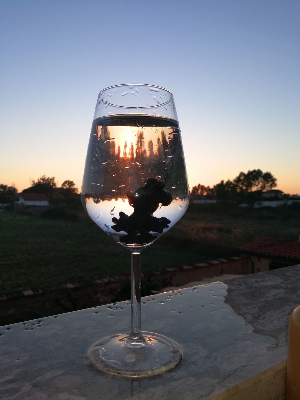 CLOSE-UP OF WINE GLASS ON TABLE AGAINST SKY