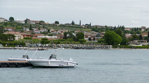 Sailboats in sea by townscape against sky