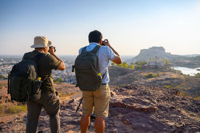 Rear view of man photographing against sky