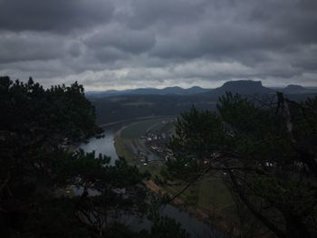 Scenic view of river by mountains against storm clouds