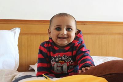 Portrait of happy baby boy on bed at home