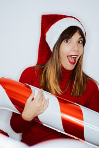 Portrait of smiling woman holding balloon while standing against white background