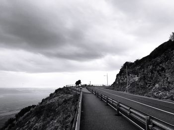 Rear view of person on road by sea against sky