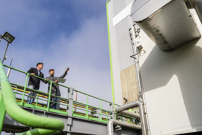 Businessman gesturing and discussing with colleague at recycling plant