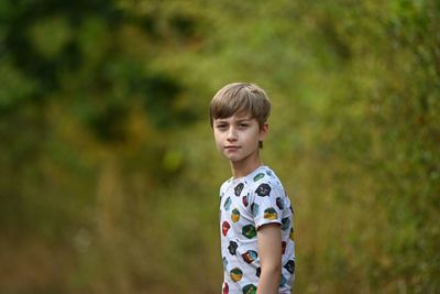 Portrait of young boy standing against trees