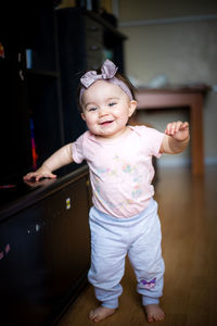 Portrait of cute smiling baby girl wearing headband at home