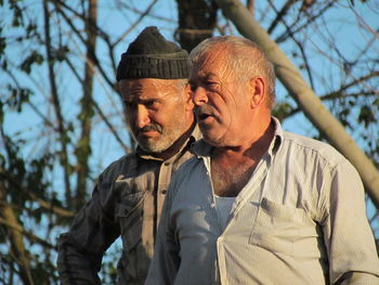 Close-up of mature men standing against bare tree