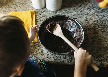 High angle view of boy making chocolate sauce in kitchen