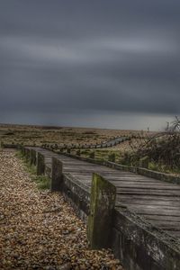 Footpath leading towards landscape against sky