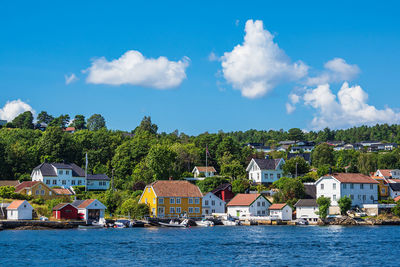 Houses by lake against sky