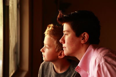 Side view close-up of mother and son looking through window at home