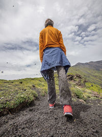 Rear view of man standing on mountain against sky