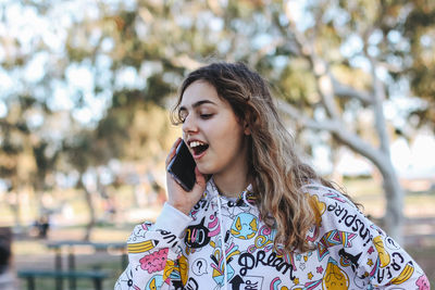 Teenager girl talking on phone while looking away while standing in park