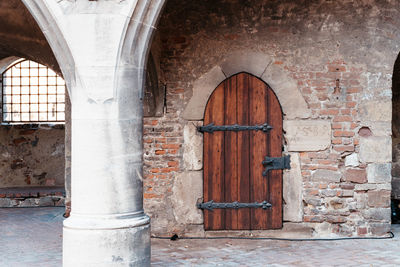 Old wooden door in a medieval castle with a white column in front