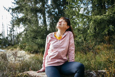 A young beautiful girl sits on a log in the forest and enjoys nature and loneliness. rest 