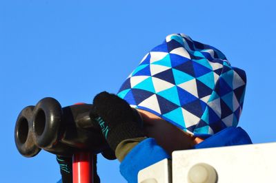 Close-up of person using binoculars against sky