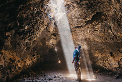 Man admires a light beam that cuts through the cave