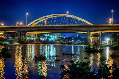 Illuminated bridge over river against sky at night