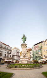 Statue in city against clear sky