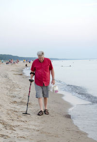 Man on the beach searching for treasure with a metal detector