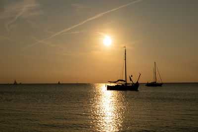 Silhouette sailboats in sea against sky during sunset