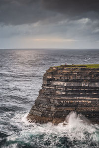 Fisherman standing on the edge of tall downpatrick head cliffs, ireland