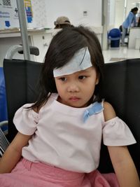 Close-up of girl with bandage on head sitting in hospital