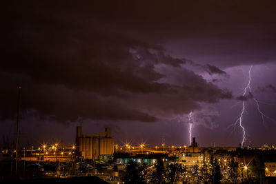 Lightning over illuminated cityscape at night