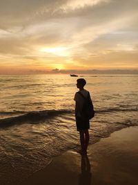 Full length of man standing on beach during sunset