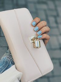 Cropped hand of woman with painted nails holding bag outdoors