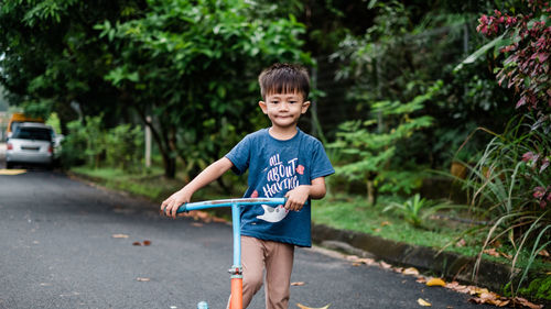 Portrait of boy standing on road in city